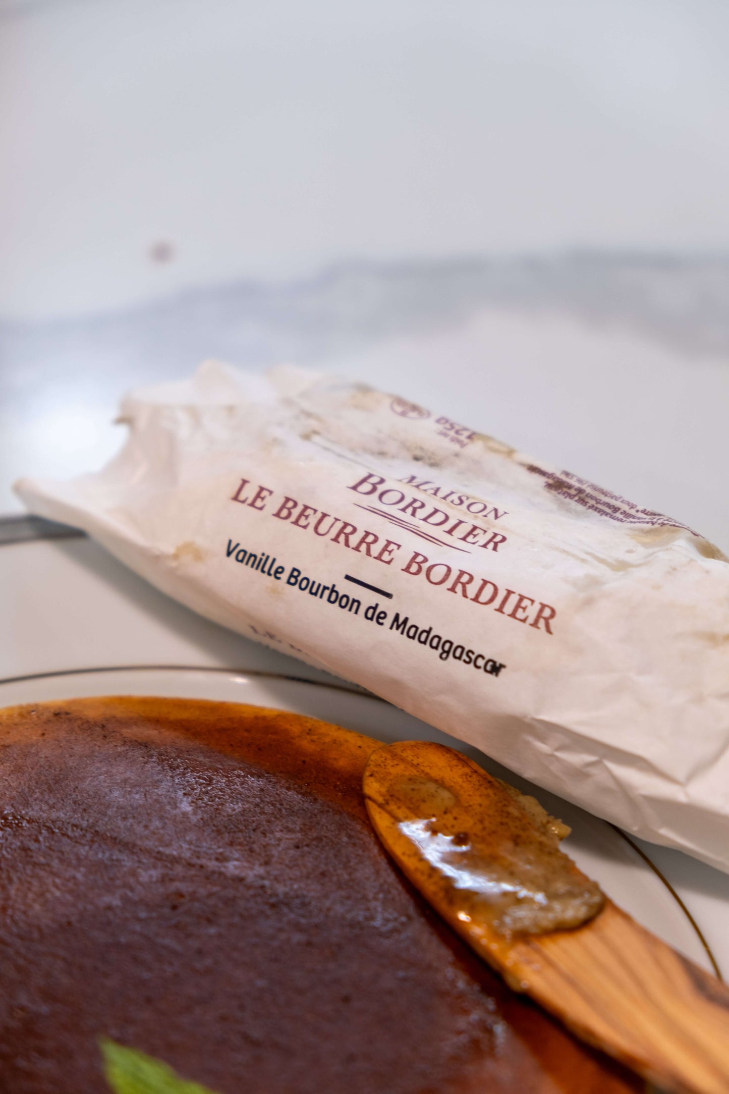 Le Beurre Bordier Madagascar Bourbon Vanilla Butter package beside a creamy dessert on a plate.