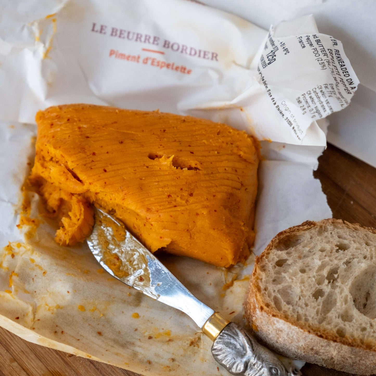 Le Beurre Bordier Espelette Pepper Butter spread beside a slice of bread.