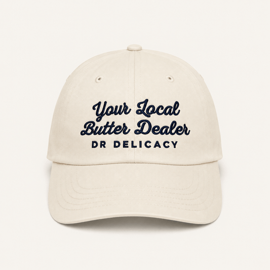 Butter Embroidered Hat featuring 'Your Local Butter Dealer' and DR Delicacy logo in blue embroidery on a stone-washed cap.