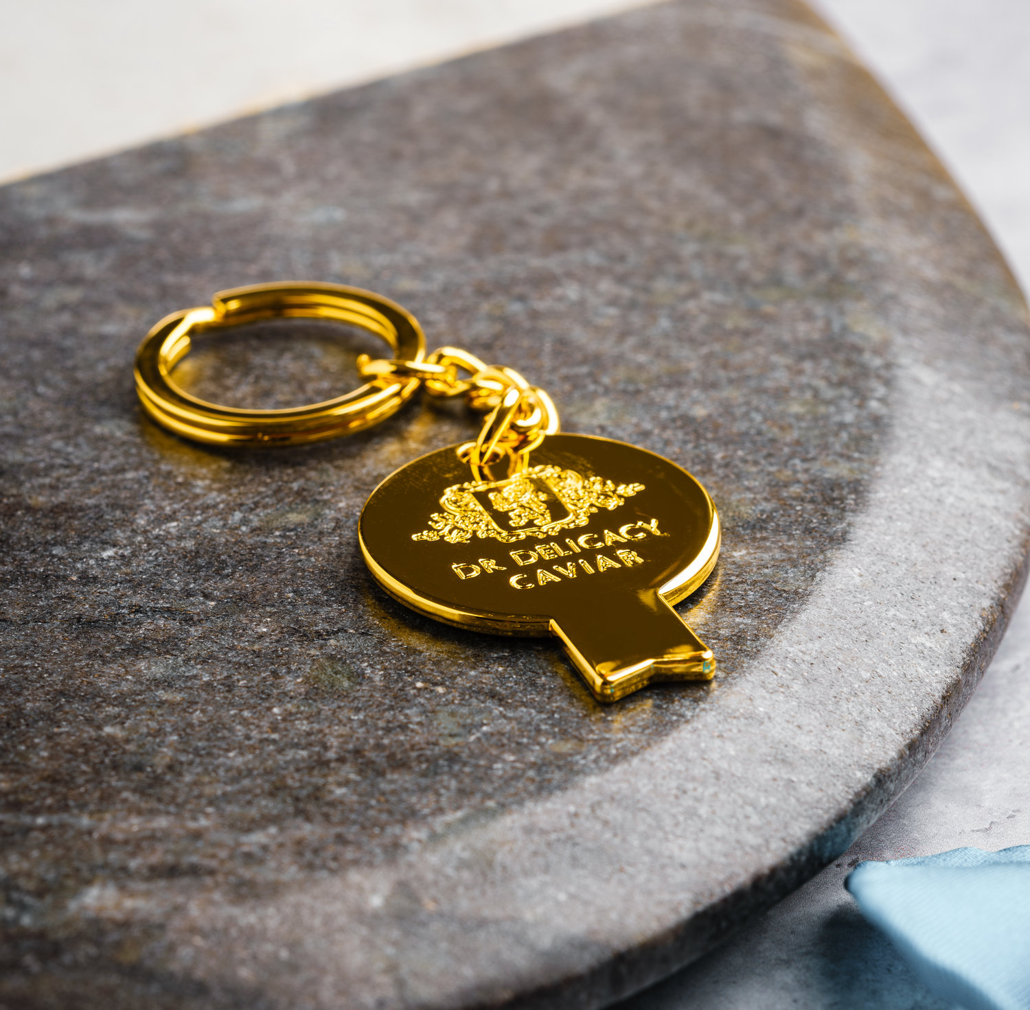Gold Caviar Key with Keychain resting on a granite surface, designed for easy caviar jar opening.