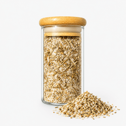 Fleur de Sel French Blend – Provençal Herb Finishing Salt in a glass jar with bamboo lid and herbal sea salt spilled out.
