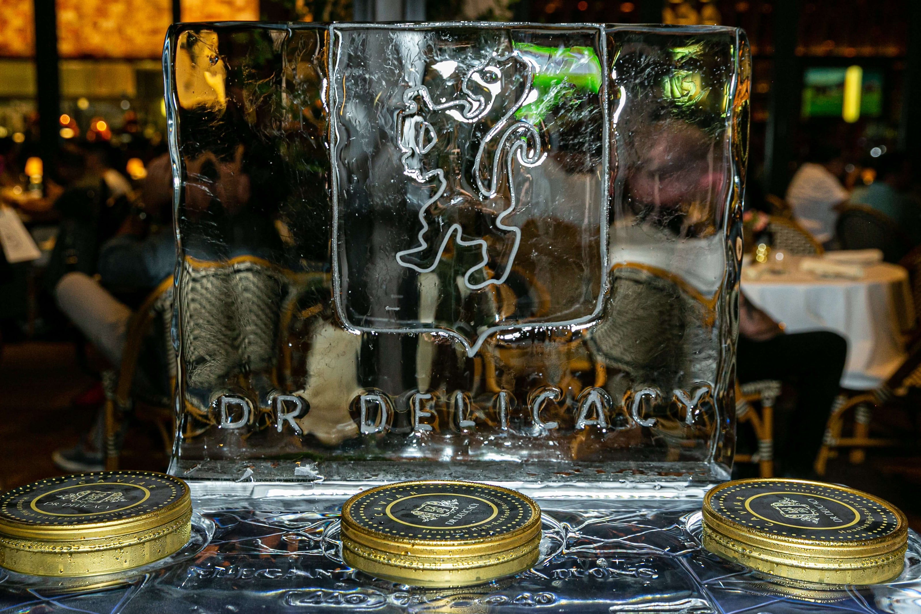 Ice sculpture with a lion emblem and gold tins at a dining venue, creating an elegant atmosphere.