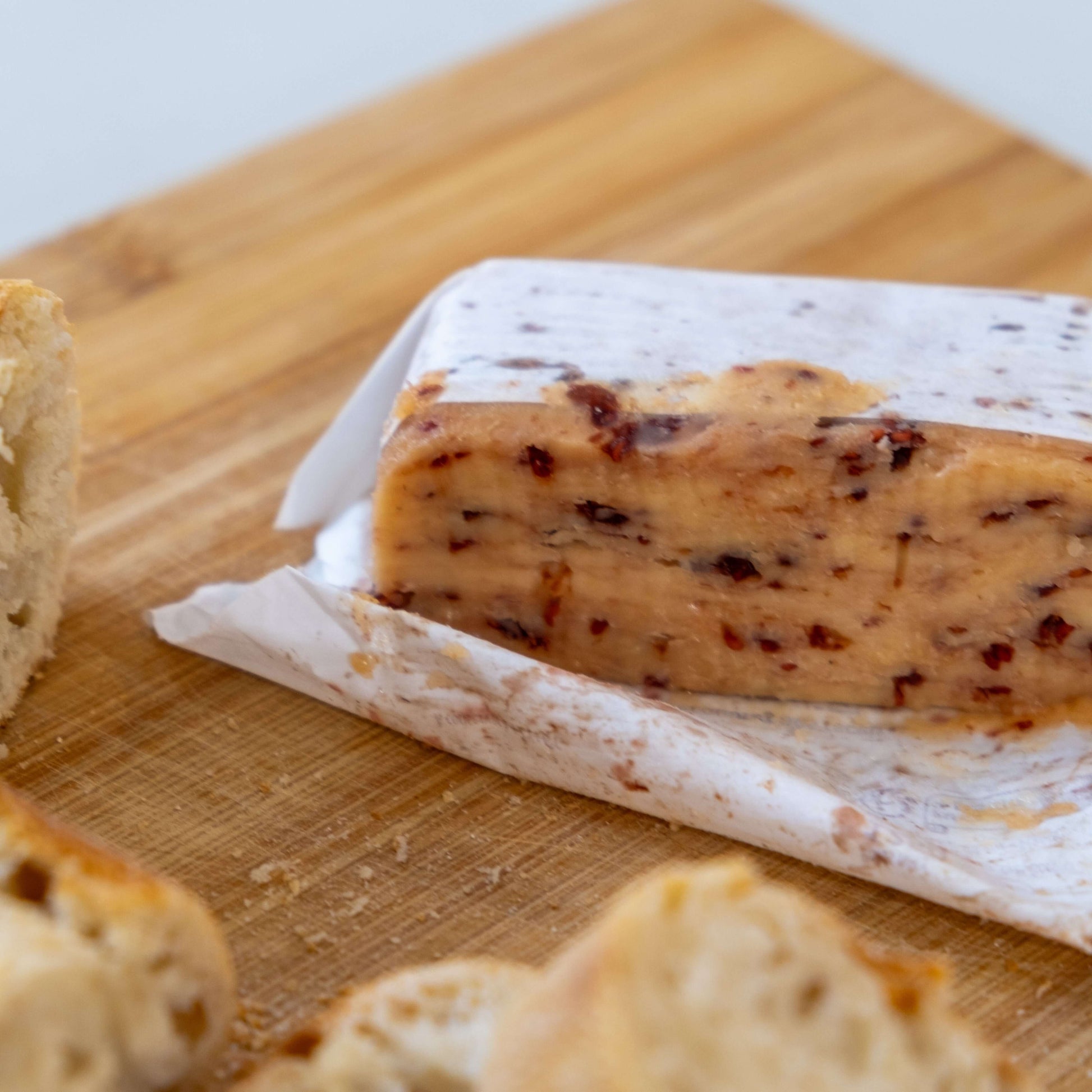 Le Beurre Bordier Raspberry Butter on a wooden cutting board, surrounded by fresh bread.