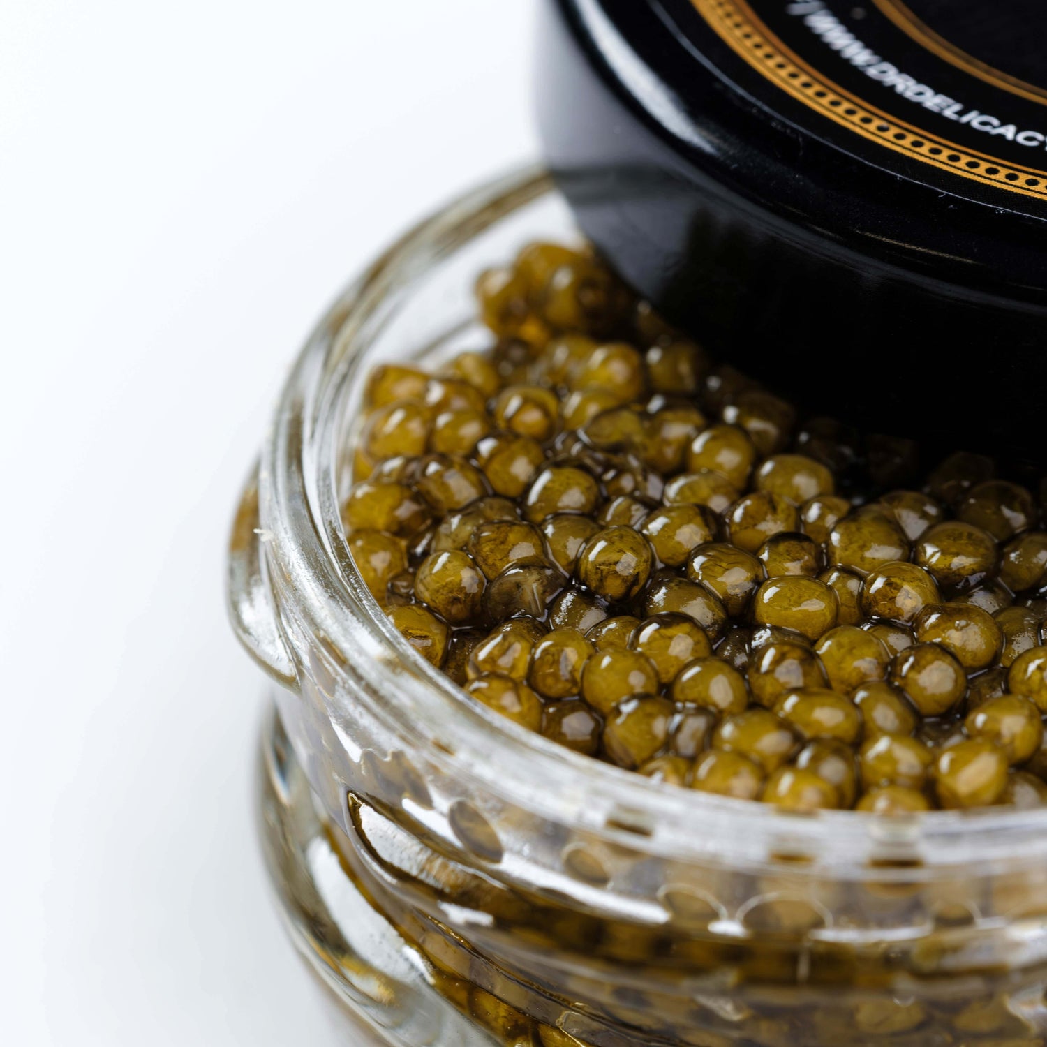 Close-up of a glass jar filled with glistening golden caviar, showcasing its unique texture and color.