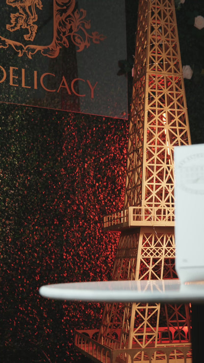 Eiffel Tower model at Delicacy event with decorative background and soft lighting