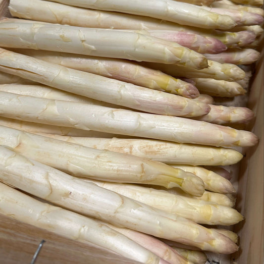 Box of white asparagus on a wooden surface